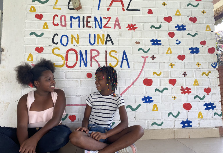 En Colombie, deux filles sous un mur avec des écritures