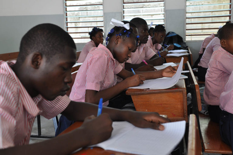 Des enfants en uniformes écrivent dans une classe à Haïti