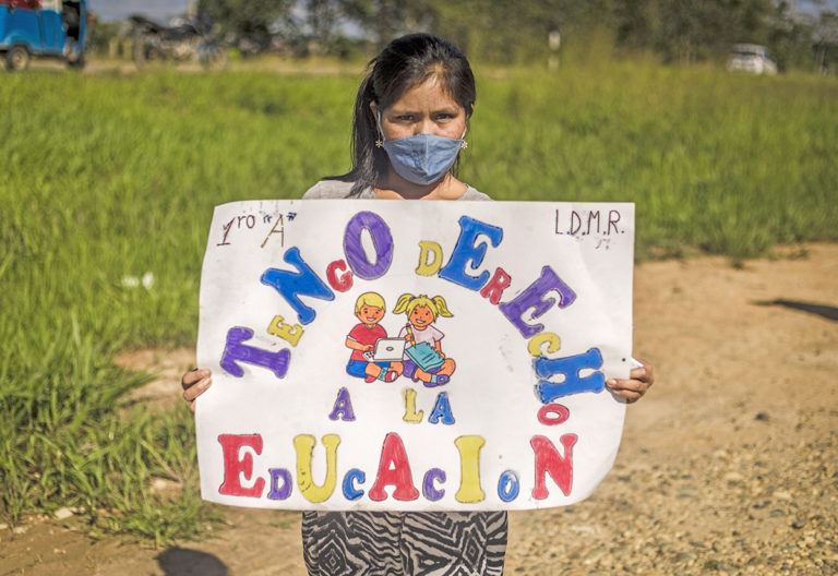 Une jeune péruvienne tient une pancarte faisant allusion au droit à l'éducation