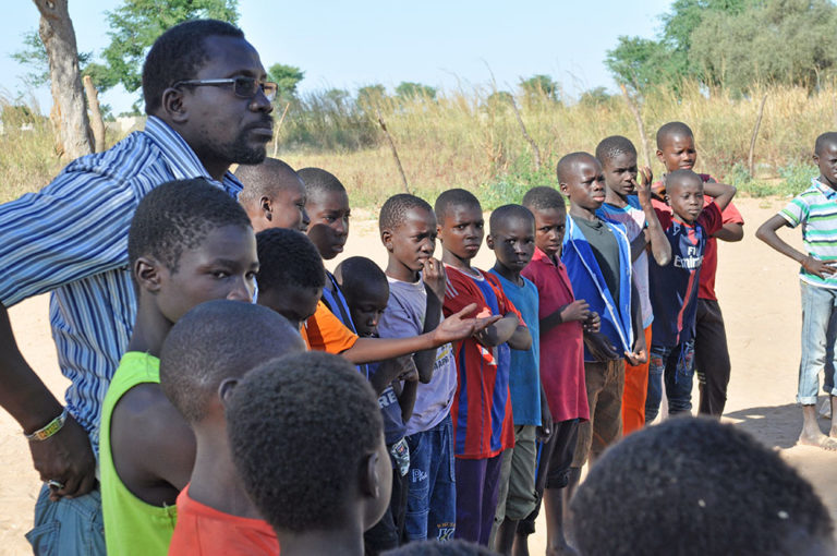 Des enfants du Sénégal en rang semblent écouter un orateur
