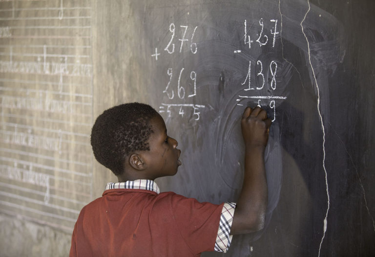 Un enfant écrit au tableau noir dans une classe du Mali
