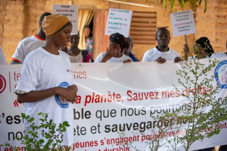 Une jeune fille devant un panneau "Sauvez ma planète, sauvez mes droits" au Mali
